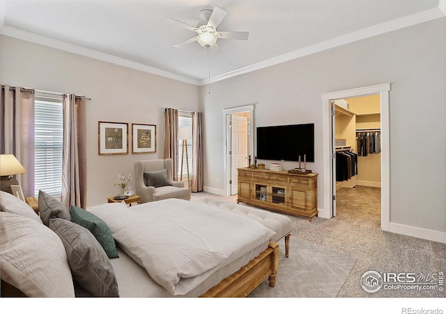 bedroom with a closet, light colored carpet, a spacious closet, ornamental molding, and baseboards