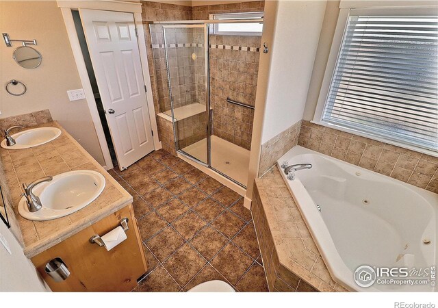 full bathroom featuring a sink, a shower stall, a whirlpool tub, and double vanity