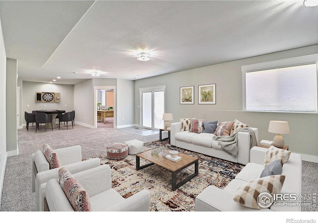 carpeted living area with baseboards and a textured ceiling