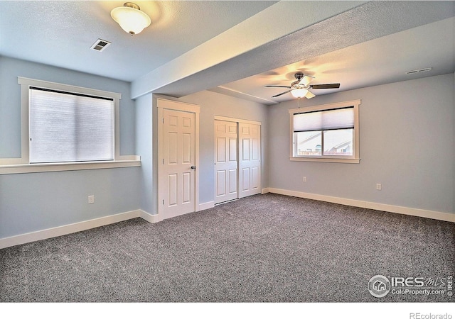 unfurnished bedroom featuring carpet, a textured ceiling, visible vents, and baseboards