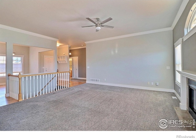 unfurnished living room featuring crown molding, light carpet, a fireplace with flush hearth, and baseboards