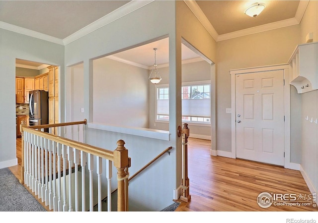 entrance foyer with ornamental molding, light wood-style flooring, and baseboards