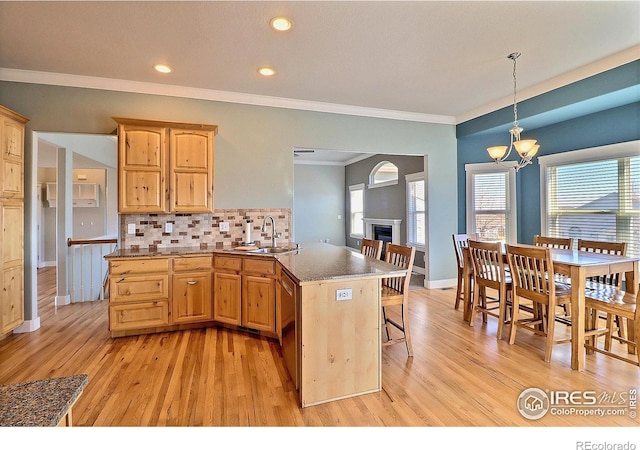 kitchen featuring tasteful backsplash, a chandelier, a fireplace, and light wood finished floors