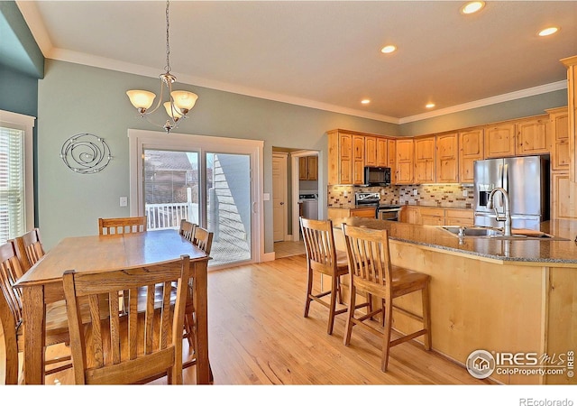 kitchen featuring a sink, light wood-style floors, ornamental molding, appliances with stainless steel finishes, and decorative backsplash