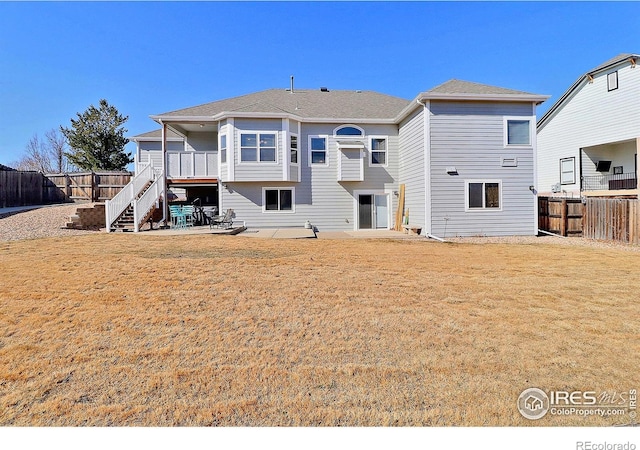 back of house with stairs, a lawn, a patio area, and a fenced backyard