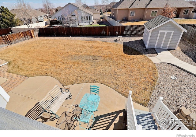 view of yard featuring a storage unit, a patio area, a residential view, a fenced backyard, and an outdoor structure