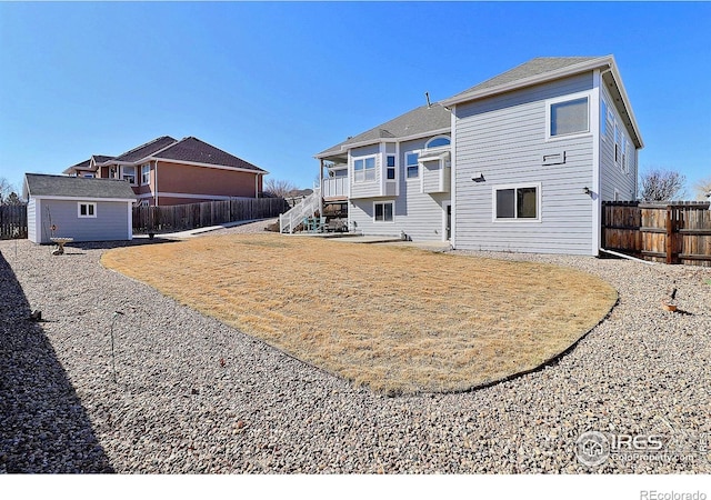 rear view of house with an outbuilding, a fenced backyard, and stairs