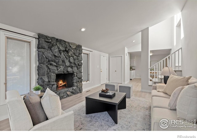 living room featuring baseboards, wood finished floors, stairs, a fireplace, and recessed lighting