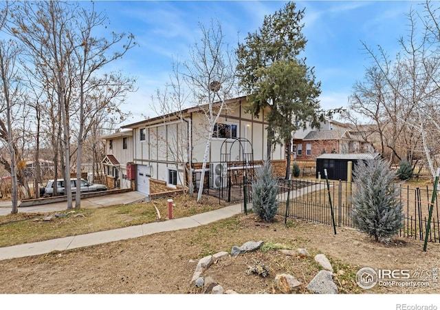 view of front of home with a garage, concrete driveway, and fence