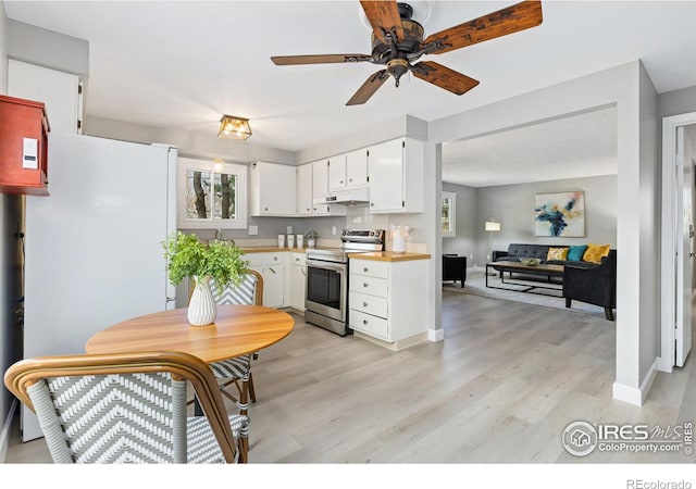 kitchen with under cabinet range hood, light wood-style floors, freestanding refrigerator, and stainless steel range with electric cooktop