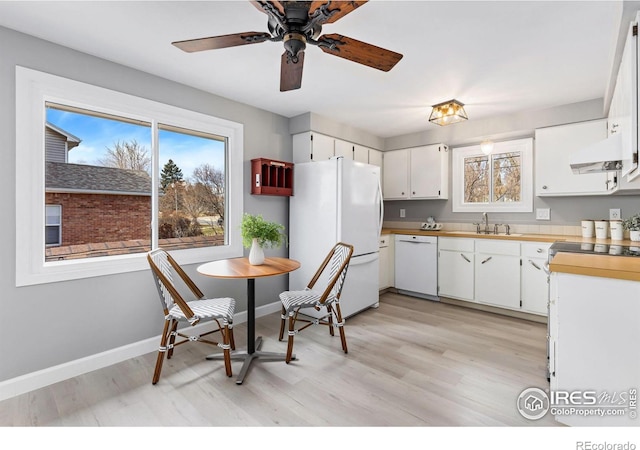 kitchen with light wood finished floors, white cabinetry, a sink, white appliances, and baseboards