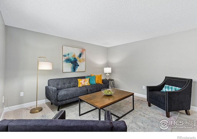 living room featuring a textured ceiling, baseboards, and wood finished floors