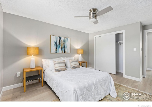 bedroom with a closet, a textured ceiling, baseboards, and wood finished floors