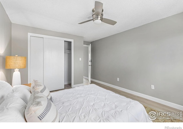 bedroom featuring baseboards, ceiling fan, a textured ceiling, light wood-style floors, and a closet