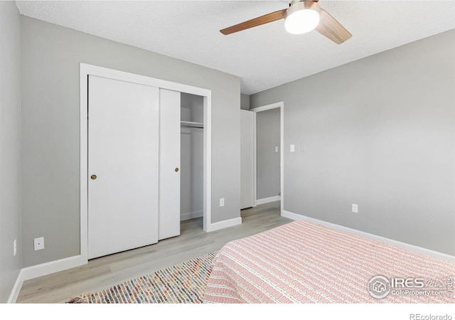 bedroom featuring a closet, ceiling fan, a textured ceiling, wood finished floors, and baseboards