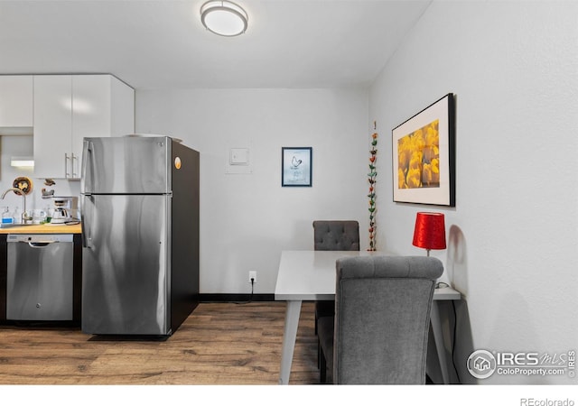 kitchen featuring a sink, appliances with stainless steel finishes, wood finished floors, and white cabinets