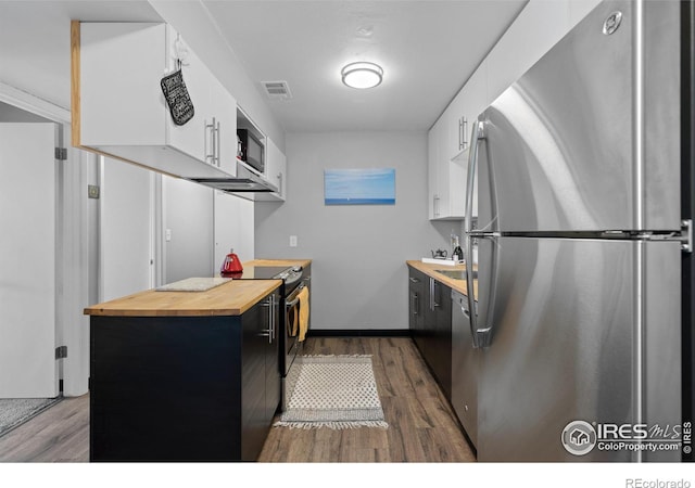 kitchen with dark wood-style floors, wooden counters, appliances with stainless steel finishes, and white cabinets