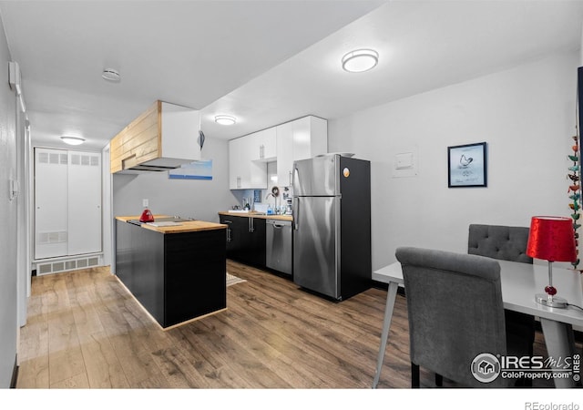 kitchen featuring stainless steel appliances, wooden counters, wood finished floors, and visible vents