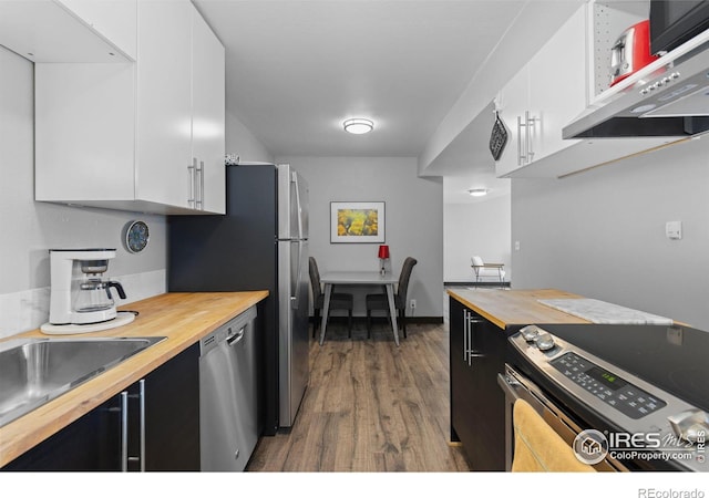 kitchen featuring under cabinet range hood, butcher block countertops, appliances with stainless steel finishes, and white cabinets