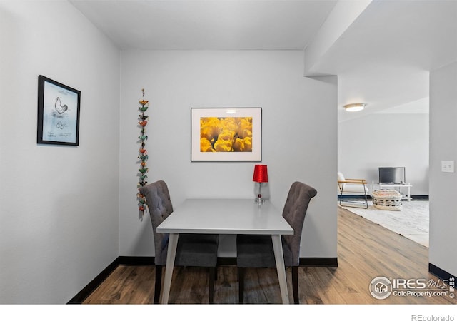 dining space with baseboards and wood finished floors