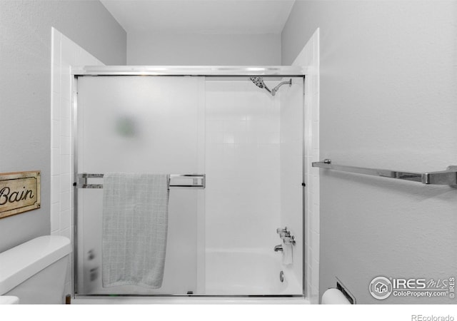 bathroom with toilet and bath / shower combo with glass door