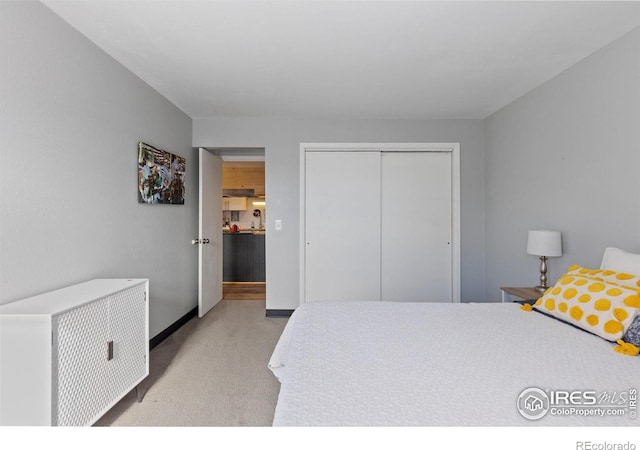 bedroom with light carpet, a closet, and baseboards