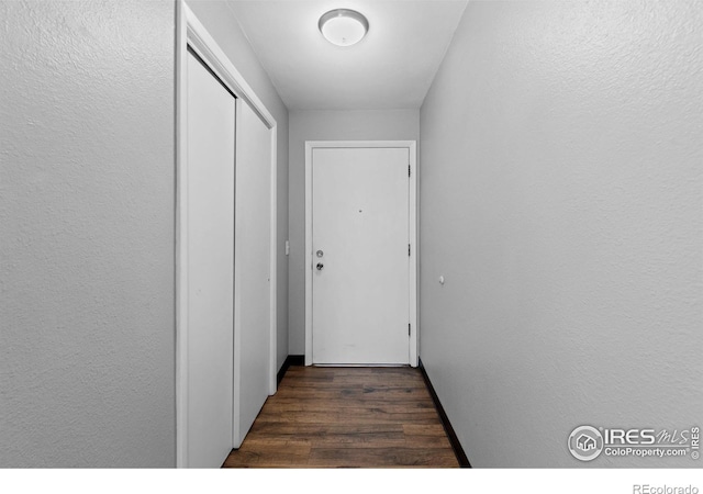 doorway to outside featuring a textured wall and dark wood finished floors