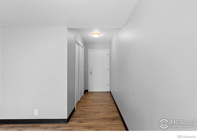 hall with baseboards and wood finished floors