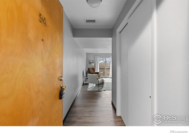 hallway with dark wood-style floors, baseboards, and visible vents