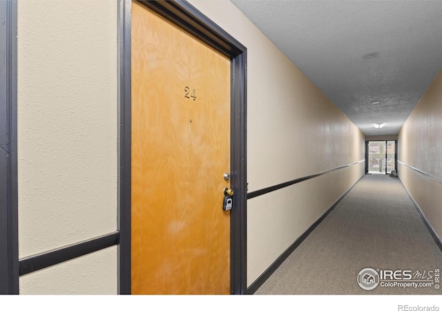 hall with a textured ceiling and carpet floors