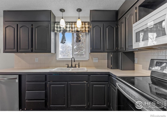 kitchen featuring light countertops, appliances with stainless steel finishes, a sink, and decorative backsplash