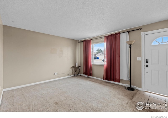 carpeted foyer featuring a textured ceiling and baseboards