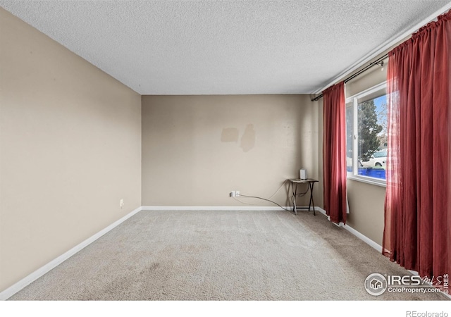 carpeted empty room with baseboards and a textured ceiling