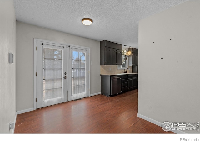 kitchen featuring tasteful backsplash, dishwashing machine, dark wood-type flooring, light countertops, and french doors