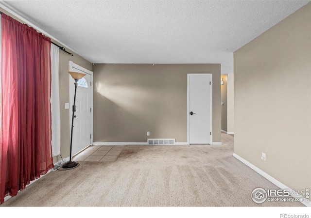 carpeted empty room with a textured ceiling, visible vents, and baseboards