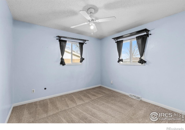 carpeted empty room featuring baseboards, visible vents, and a textured ceiling