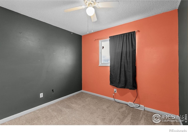 carpeted spare room featuring a ceiling fan, baseboards, and a textured ceiling