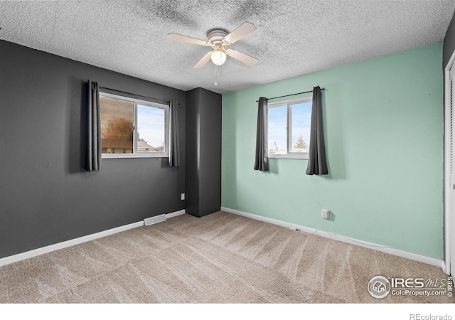 spare room with carpet floors, a healthy amount of sunlight, a textured ceiling, and baseboards