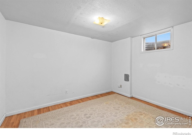 spare room featuring a textured ceiling, baseboards, and wood finished floors