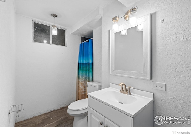 bathroom featuring toilet, a textured wall, wood finished floors, and vanity