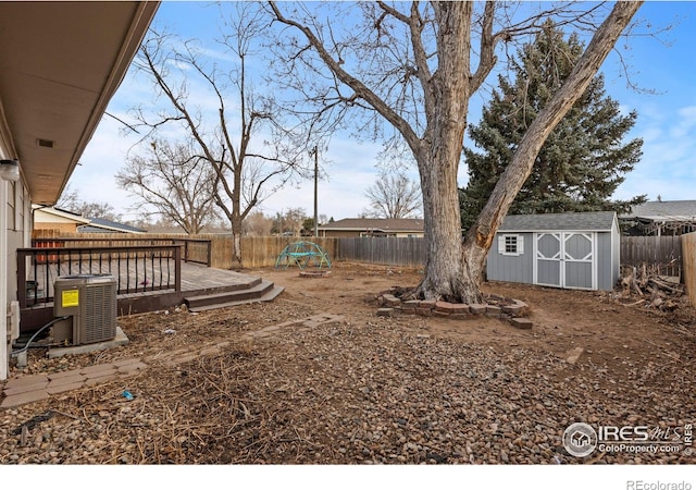 view of yard with central AC unit, a fenced backyard, a storage unit, a wooden deck, and an outdoor structure