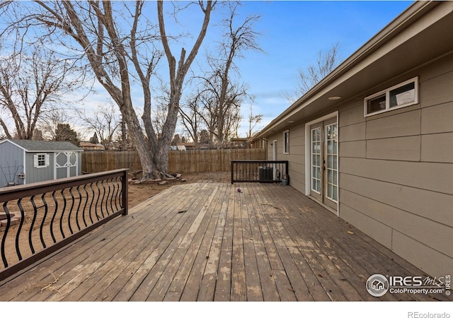 wooden deck featuring an outbuilding, french doors, a fenced backyard, and a storage unit