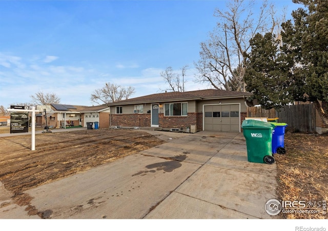 ranch-style home with a garage, fence, concrete driveway, and brick siding