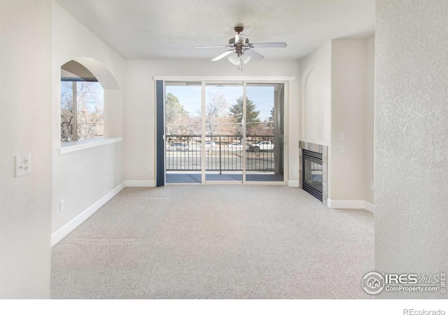 unfurnished living room with carpet, baseboards, a ceiling fan, and a glass covered fireplace