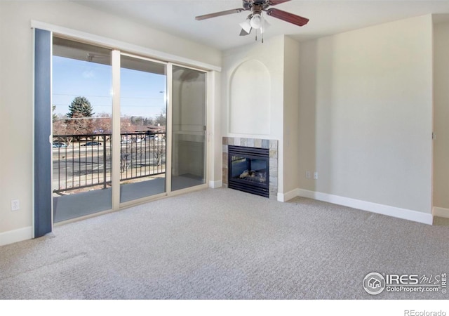 unfurnished living room featuring a ceiling fan, a tiled fireplace, baseboards, and carpet flooring