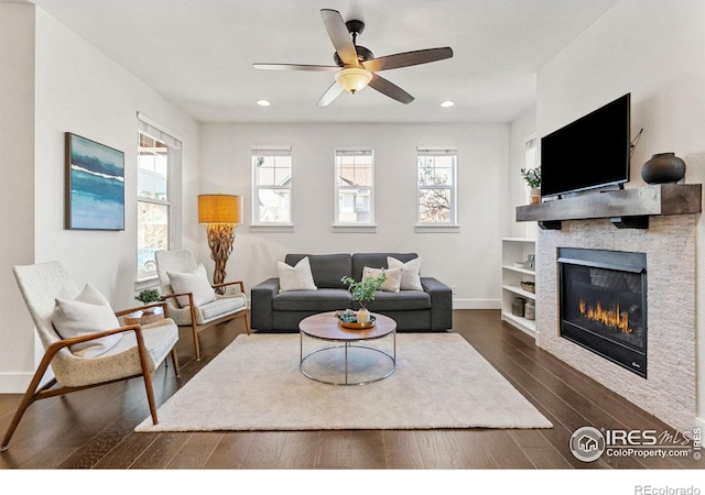 living room featuring dark wood-style floors, a glass covered fireplace, baseboards, and recessed lighting