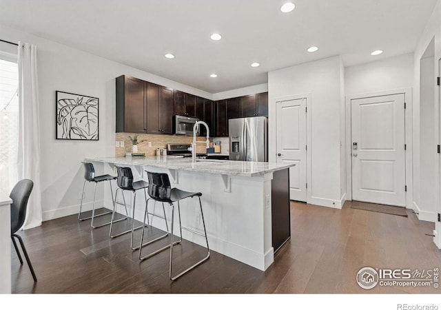 kitchen featuring dark wood-style floors, a breakfast bar, a peninsula, stainless steel appliances, and a sink