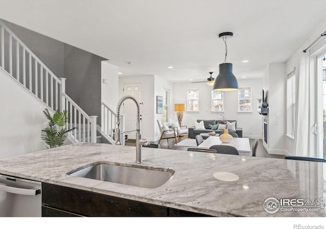 kitchen featuring recessed lighting, a sink, open floor plan, hanging light fixtures, and stainless steel dishwasher