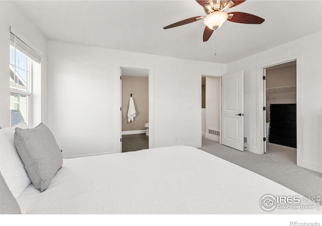 carpeted bedroom featuring visible vents, connected bathroom, a spacious closet, and baseboards