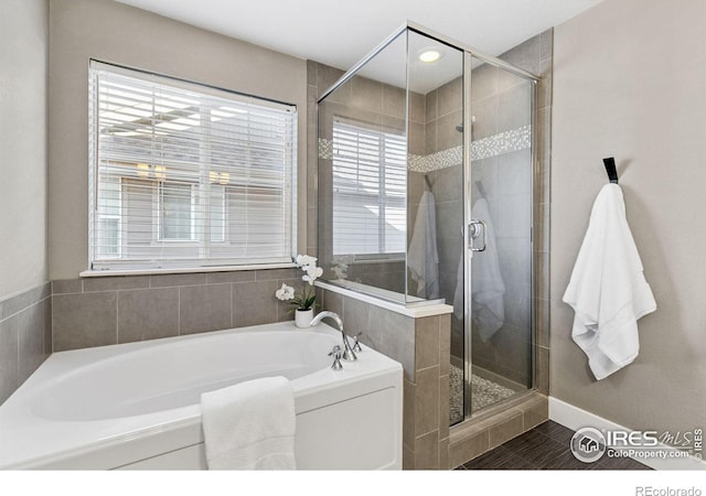 full bath featuring a shower stall, a bath, and baseboards